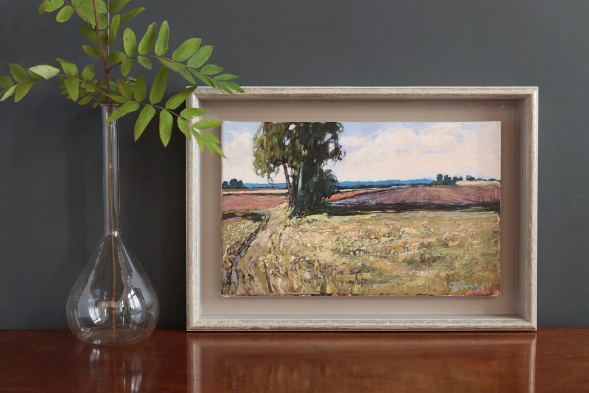 Pejzaż. Obraz malowany ręcznie. Autor Krzysztof Nowak. Na obrazie drzewo i pole. Obok obrazu wazon.