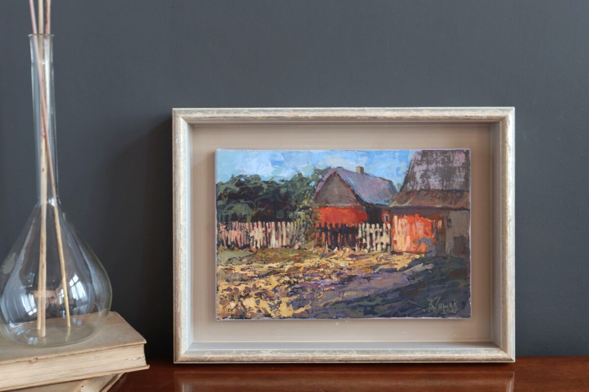 Mały obraz ręcznie malowany. Na obrazie wieś i chata. Impresjonizm. Autor Krzysztof Nowak. Obok obrazu stoi wazon.